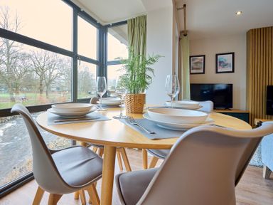 A dining room with a round table set for meals at Riverside Park 3 in Keswick