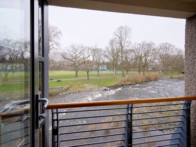 A view from a balcony overlooking a river and trees at Riverside Park 3 Keswick