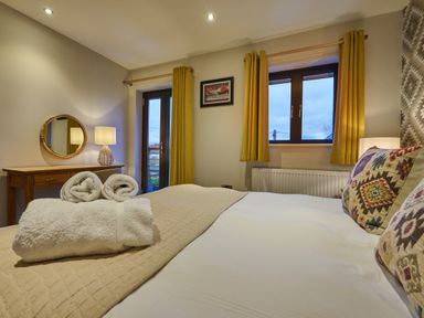 A bedroom with a bed, towels, and a mirror at Riverside Park 5 in Keswick