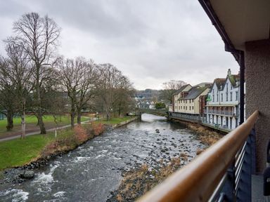 A view of a river with trees and buildings along the bank at Riverside Park 5 in Keswick