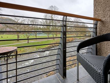 A balcony overlooking a river and park at Riverside Park 5 Keswick