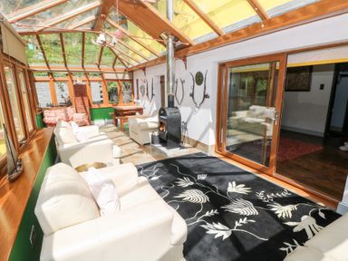 A conservatory with seating and a stove at The Woodlands Lower Level Stepaside