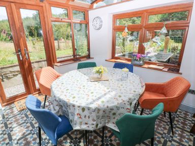 A conservatory with a round table and chairs at The Woodlands Lower Level in Stepaside