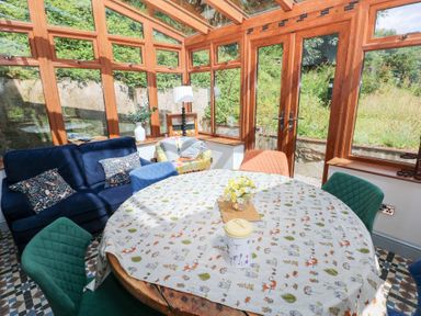 A conservatory with a table and chairs at The Woodlands Lower Level Stepaside