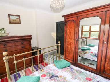 A bedroom with a bed, wardrobe, and chest of drawers at The Woodlands Lower Level in Stepaside
