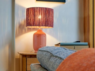 A bedside table with a lamp shaped like a face next to a bed at Riverside Park 6 in Keswick