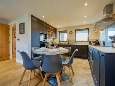 A kitchen with a round dining table set for six and dark cabinets at Riverside Park 6 in Keswick