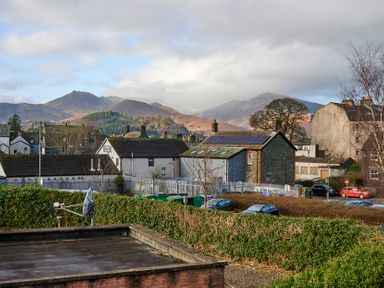 A view of houses and parked cars with mountains in the background at Riverside Park 6 in Keswick