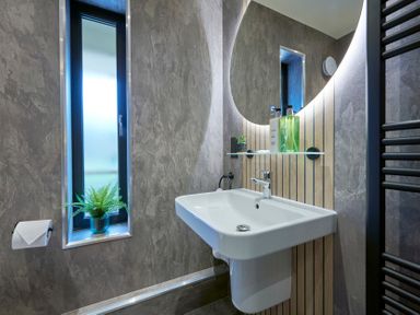 A bathroom with a sink mirror a window with a plant and a toilet paper holder at Riverside Park 6 in Keswick