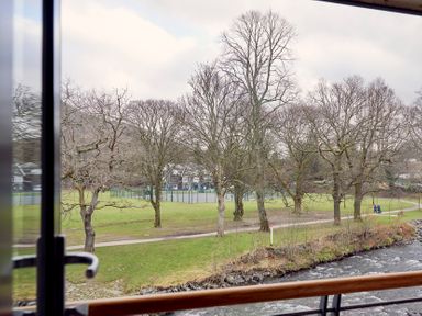 A view of a riverside park with leafless trees a walking path and tennis courts in the background at Riverside Park 6 in Keswick