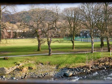 A park with trees a tennis court and a river in Riverside Park 6 Keswick