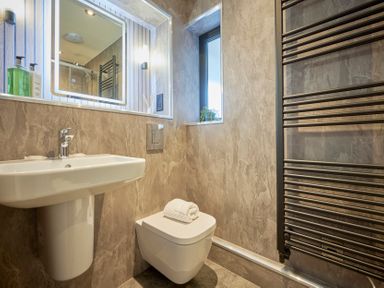 A bathroom with a wall mounted sink toilet and towel radiator at Riverside Park 6 in Keswick