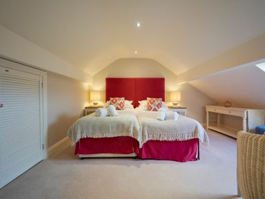 A bedroom with two single beds with red headboards and beige throws at Riverside Park 6 in Keswick
