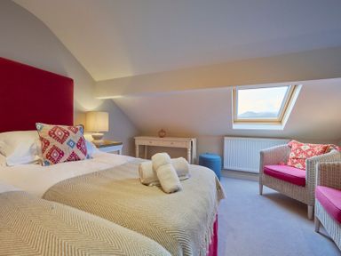 A bedroom with a bed a bedside table and lamp a window wicker chairs and a small table at Riverside Park 6 in Keswick