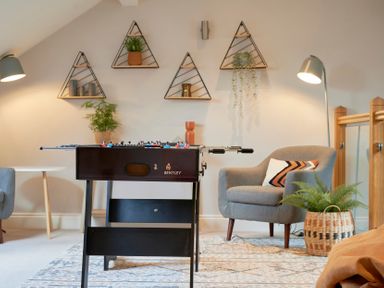 A game room with a foosball table, chairs, wall shelves with plants and decor at Riverside Park 6 in Keswick