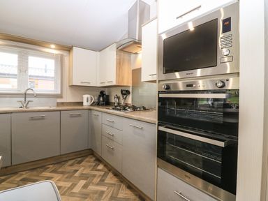 A kitchen with built in oven microwave cupboards countertop sink and gas stove at Woodpecker Lodge Dunbar