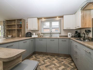 A kitchen with cabinets appliances and a window at Woodpecker Lodge in Dunbar