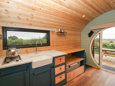 A kitchen area with a sink stove and countertop next to a round door at Lime Kiln in Blagdon