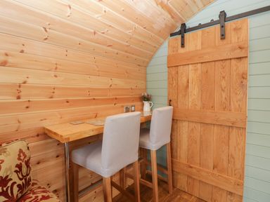A small wooden table with two high chairs and a sliding wooden door at Lime Kiln in Blagdon