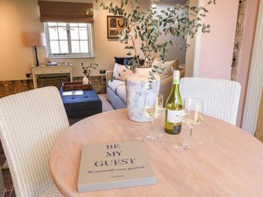 A dining table with a guestbook a bottle of wine and two wine glasses in a living area at The Forge in Old Newton near Stowmarket