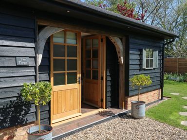 An entrance to a building with wooden doors and potted plants outside at The Forge in Old Newton near Stowmarket