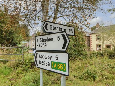 Road signs showing directions to Bleatarn Appleby and K Stephen near rural houses at Row End farm in Brough