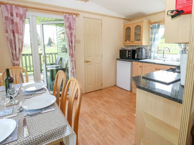 A kitchen and dining area with a table set for four people and a door leading outside at Row End farm in Brough