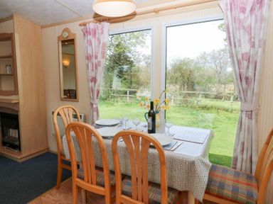 A dining area with a table set for four near large windows showing a garden at Row End farm in Brough