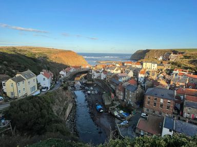 A coastal village with houses, a river with boats, cliffs, and the sea at Bethel Chapel in Staithes