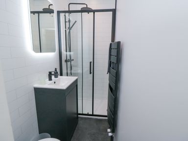 A bathroom with a sink vanity mirror shower and towel radiator at Bethel Chapel in Staithes