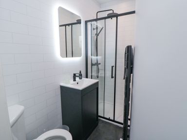 A bathroom with a toilet sink vanity mirror and glass shower enclosure at Bethel Chapel in Staithes