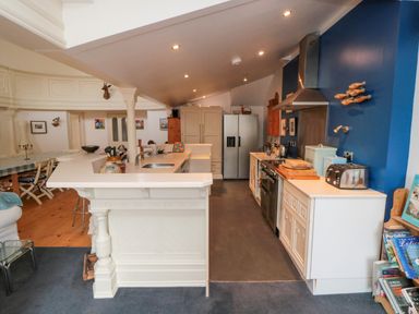 A kitchen with white cabinets and blue wall with fish decorations at Bethel Chapel in Staithes