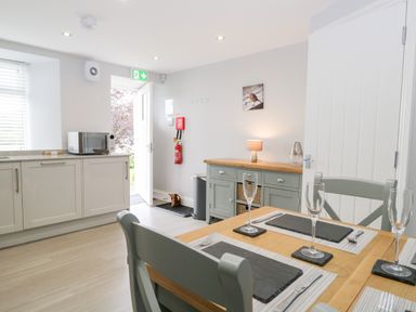 A kitchen dining area with a wooden table set with glassware and a sideboard against the wall at Oxen Park Farm Cottage Oxen Park near Ulverston