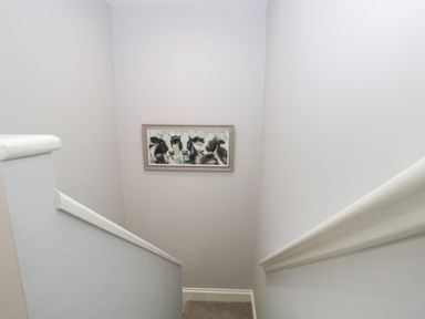 A staircase with light grey walls and a framed picture of cows at Oxen Park Farm Cottage in Oxen Park near Ulverston