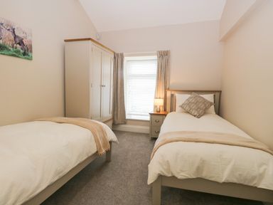 A bedroom with two single beds a wardrobe a nightstand with a lamp and a window at Oxen Park Farm Cottage Oxen Park near Ulverston