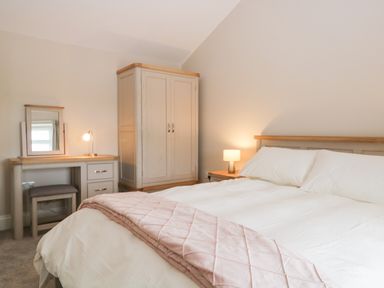 A bedroom with a bed a wardrobe and a dressing table with a lamp at Oxen Park Farm Cottage Oxen Park near Ulverston
