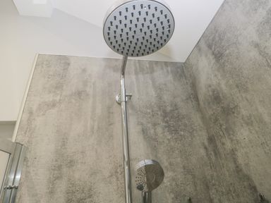 A shower area with two round shower heads and textured gray walls at Oxen Park Farm Cottage Oxen Park near Ulverston