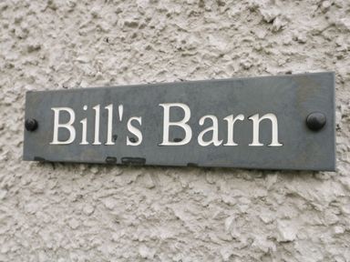 A close up of a wall sign reading Bills Barn on a textured exterior wall at Bills Barn Oxen Park near Ulverston