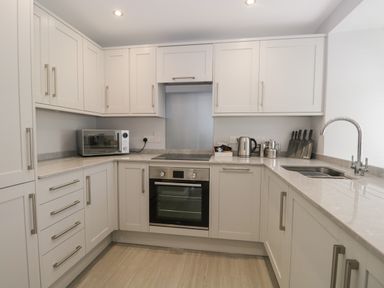 A kitchen with white cabinets a microwave kettle knives and a sink at Bill's Barn in Oxen Park near Ulverston