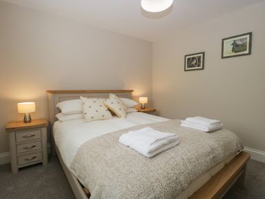 A bedroom with a double bed, two bedside tables with lamps, two pillows, and two folded towels at Bill's Barn in Oxen Park near Ulverston