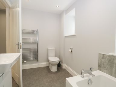 A bathroom with a toilet a chrome towel rack a white sink and a bathtub at Bill's Barn in Oxen Park near Ulverston