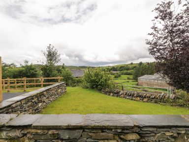 A garden with grass and stone walls overlooking a rural landscape at Bill's Barn in Oxen Park near Ulverston