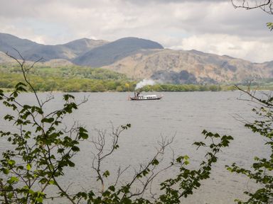 A steamboat on a lake with hills and trees in the background at Bills Barn Oxen Park near Ulverston