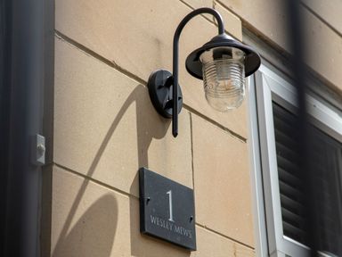 A wall-mounted light and house number sign on a building exterior at 1 Wesley Mews in Alnwick