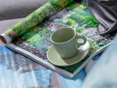 A green cup and saucer on an open magazine with colorful garden images at 1 Wesley Mews in Alnwick