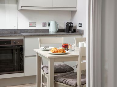 A kitchen with a table and two chairs a kettle and a coffee machine on the counter at 1 Wesley Mews in Alnwick