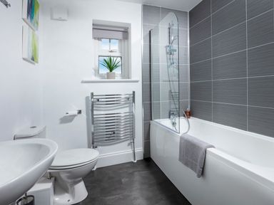 A bathroom with a bathtub shower combination toilet sink and towel radiator at 1 Wesley Mews in Alnwick