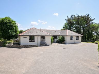 A house with a bench and trees in front at Columbine Cottage in Bude