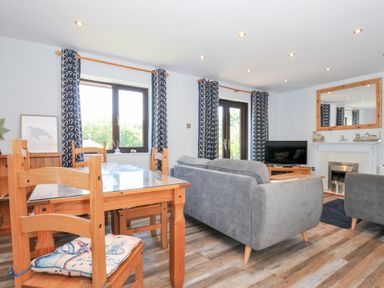 A living room with a dining table and sofa at Columbine Cottage in Bude