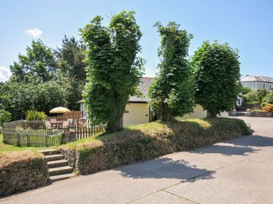 A house with trees and garden furniture at Columbine Cottage in Bude